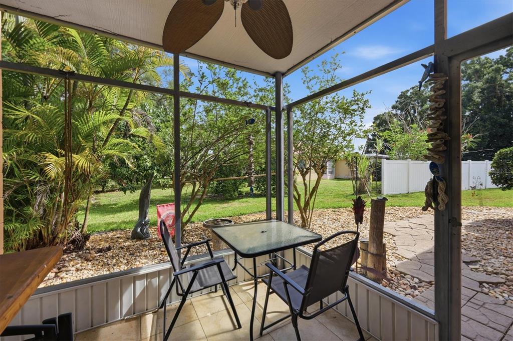 A screened-in patio features a glass-top table, two chairs, and views of a backyard — 2223 BENEVA TERRACE UNIT 2222, SARASOTA, FL