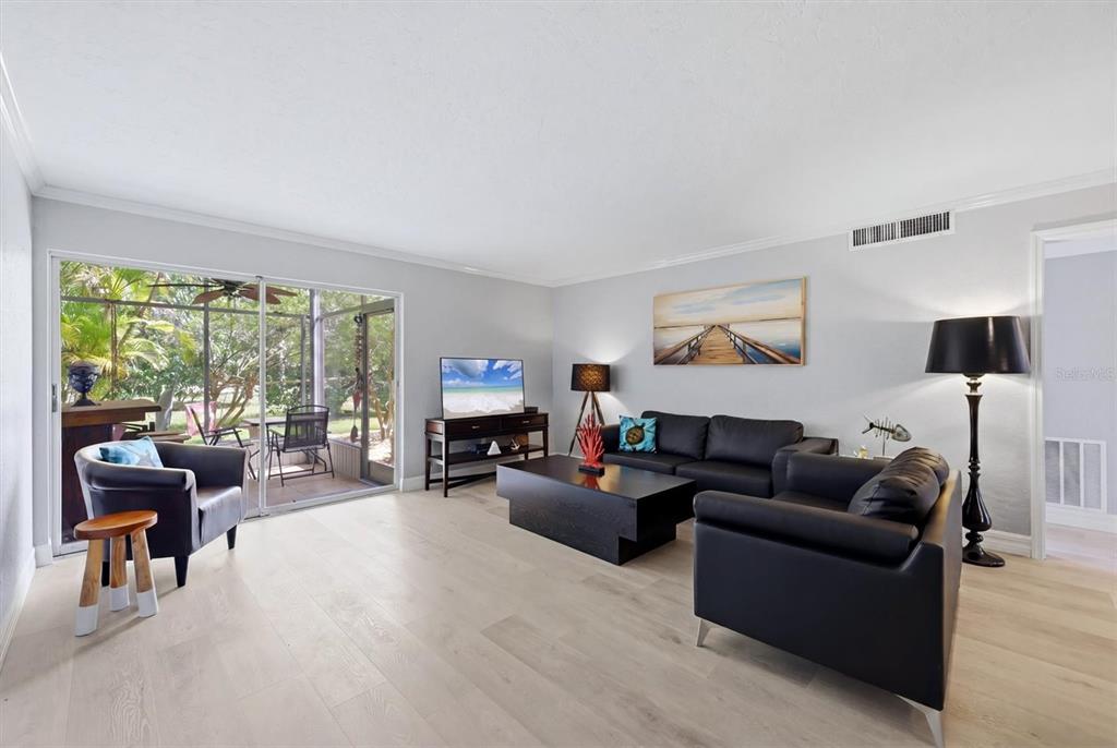 A living room features light wood flooring, black leather furniture, and a sliding glass door — 2223 BENEVA TERRACE UNIT 2222, SARASOTA, FL