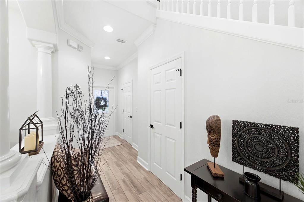 A bright entryway features light wood-look flooring, white walls, two closed doors, and decorative accents — 2670 TANGLEWOOD TRAIL, PALM HARBOR, FL