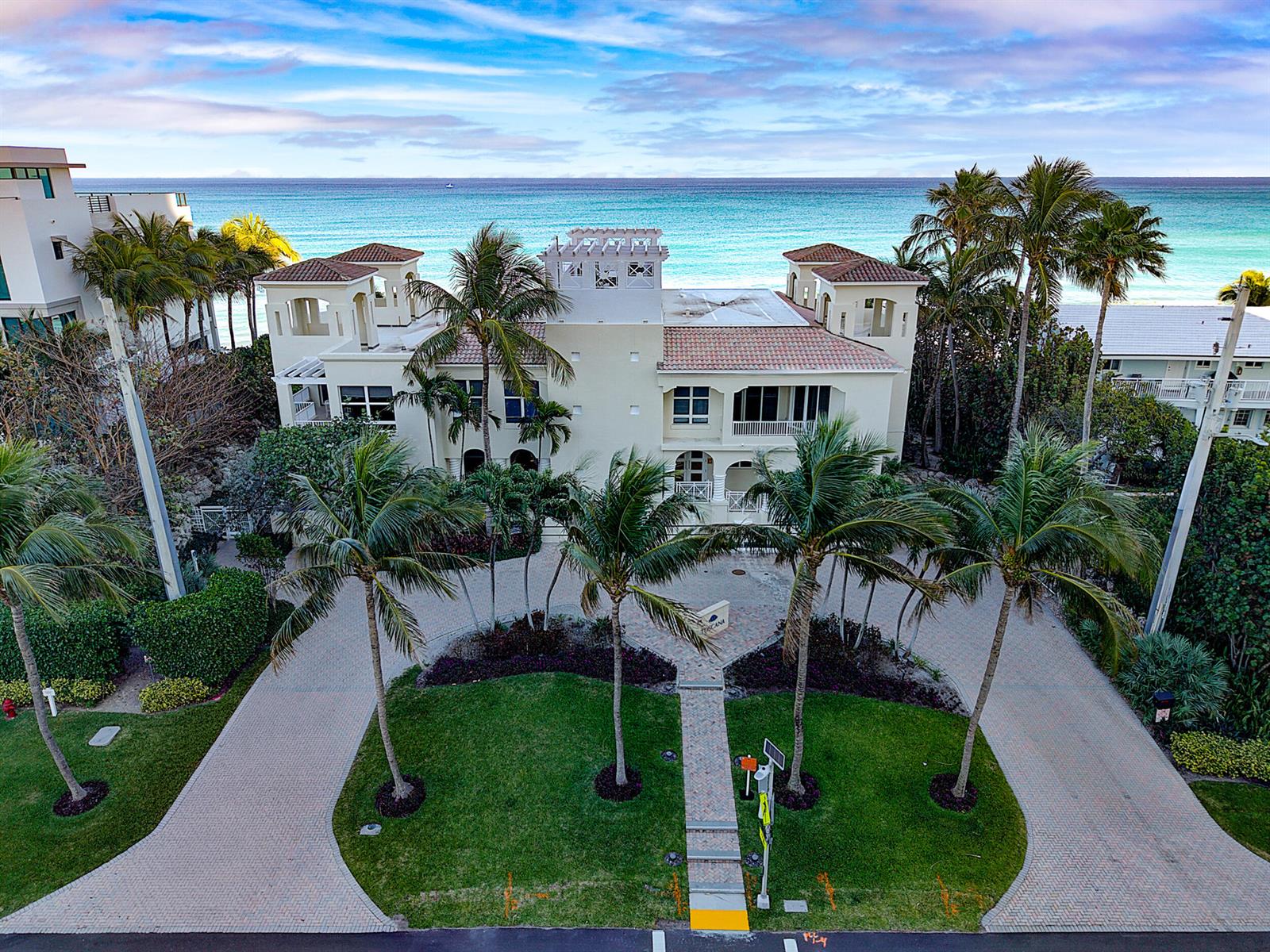 An aerial view of a multi-story Mediterranean-style villa with palm trees and a paved driveway — 3740 S Ocean Boulevard Apt 709, Highland Beach FL 33487, HIGHLAND BEACH, FL