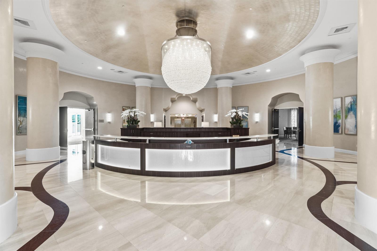 A spacious hotel lobby features a large circular reception desk, a crystal chandelier, and columns — 3740 S Ocean Boulevard Apt 709, Highland Beach FL 33487, HIGHLAND BEACH, FL