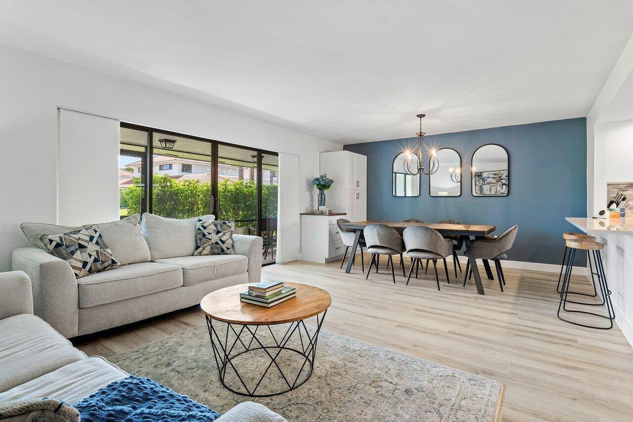 A living and dining room with light wood floors, a blue accent wall, and furniture — 4143 Kittiwake Court, Boynton Beach FL 33436, BOYNTON BEACH, FL