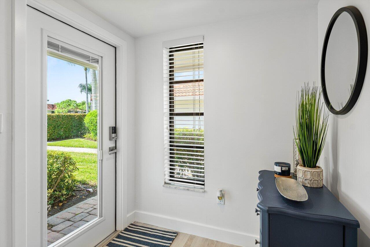 An entryway features a white door, a narrow window with blinds, and a blue cabinet — 4143 Kittiwake Court, Boynton Beach FL 33436, BOYNTON BEACH, FL