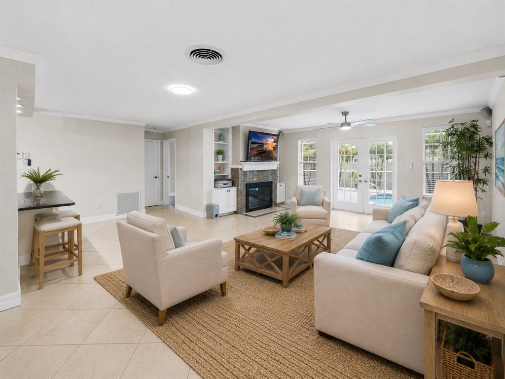 A living room features a fireplace, tile floors, a rug, and a view of a pool — 1394 BELLEVUE BOULEVARD, CLEARWATER, FL
