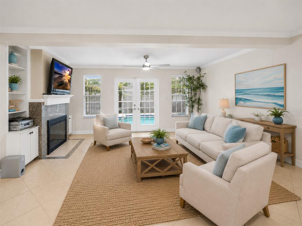 A living room features a fireplace, a beige sofa, two armchairs, and French doors — 1394 BELLEVUE BOULEVARD, CLEARWATER, FL