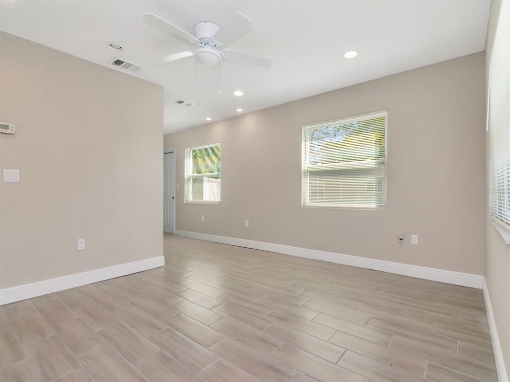 A room with light-colored walls, wood-look tile flooring, a ceiling fan, and two windows — 1211 62ND AVENUE E, BRADENTON, FL
