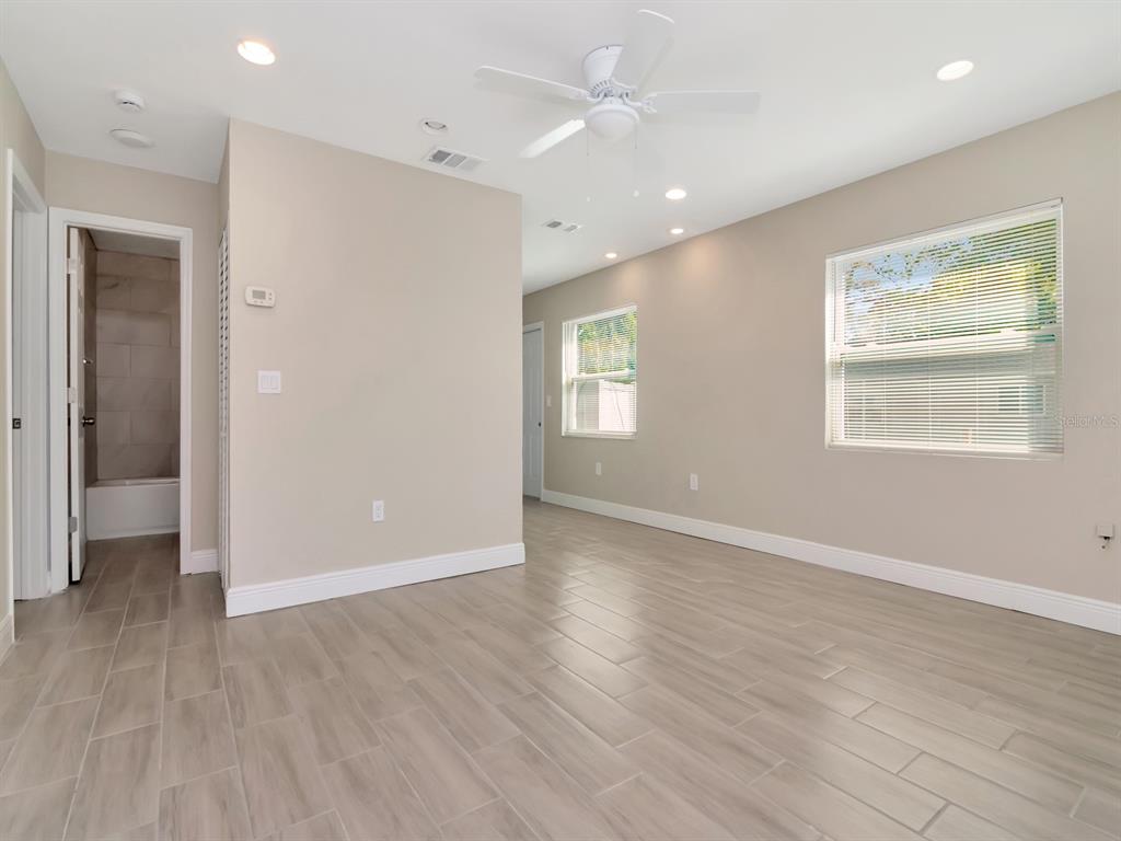 A room with light-colored walls, wood-look tile flooring, a ceiling fan, and a bathroom entrance — 1211 62ND AVENUE E, BRADENTON, FL