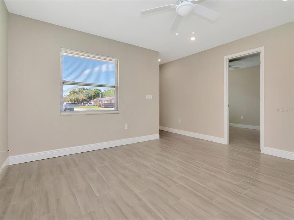 An empty room with light-colored walls, wood-look tile flooring, a ceiling fan, and a window — 1211 62ND AVENUE E, BRADENTON, FL