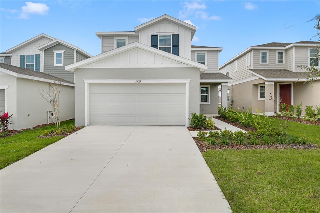 A two-story suburban house with a gray stucco facade, a two-car garage, and a driveway — 6170 DAPHNE STREET, LAKE HAMILTON, FL