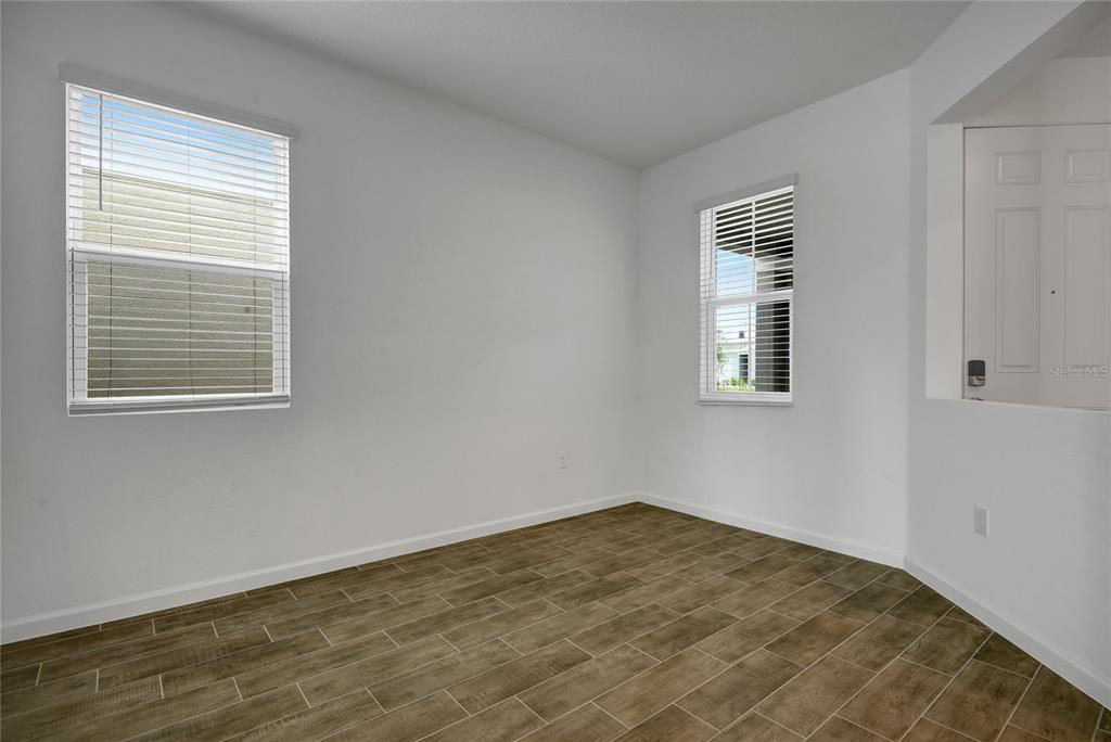 An empty room with white walls, wood-look tile flooring, and two windows with blinds — 6170 DAPHNE STREET, LAKE HAMILTON, FL