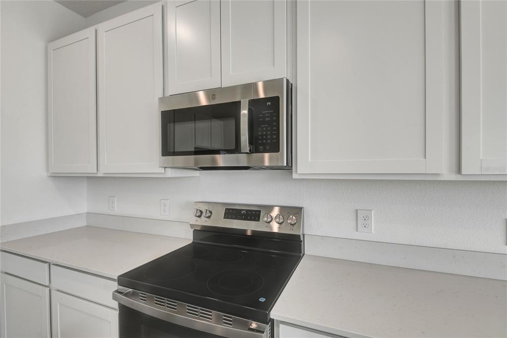 A kitchen features white cabinets, a stainless steel microwave, and a black electric range — 6170 DAPHNE STREET, LAKE HAMILTON, FL