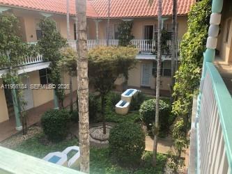 A view from a balcony overlooking a courtyard with trees, shrubs, and a tiled roof — 736 13th St # 202, Miami Beach FL 33139, MIAMI BEACH, FL