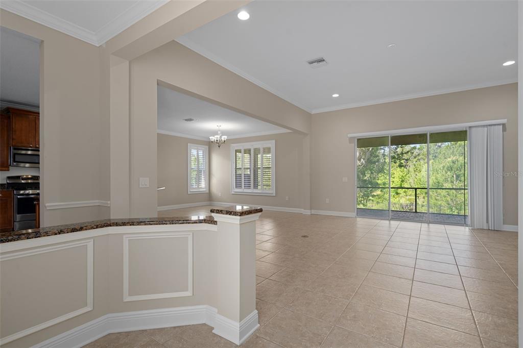An open-concept living area with tile flooring, a kitchen pass-through, and sliding glass patio doors — 4551 SOUTHERN VALLEY LOOP, BROOKSVILLE, FL