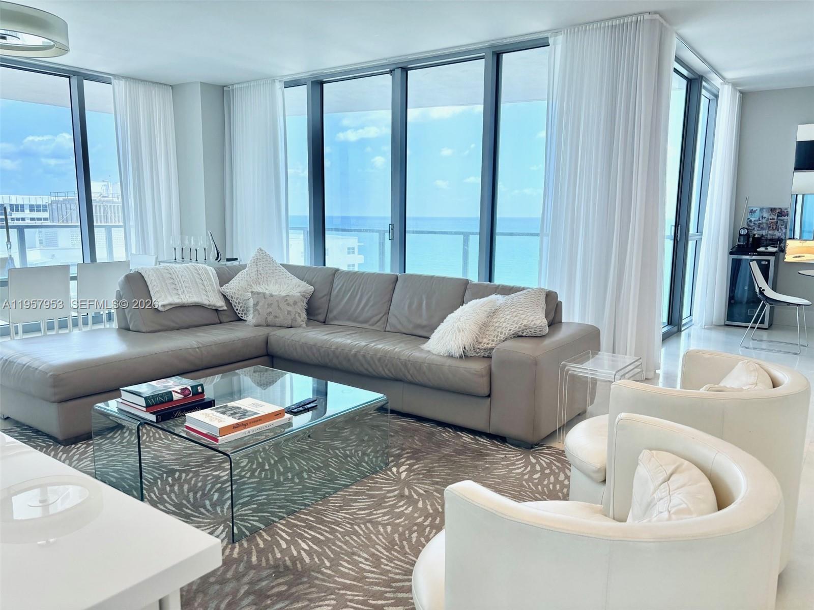 A modern living room features a gray sectional sofa, glass coffee table, and ocean views — 3101 S Ocean Dr # 1701, Hollywood FL 33019, HOLLYWOOD, FL