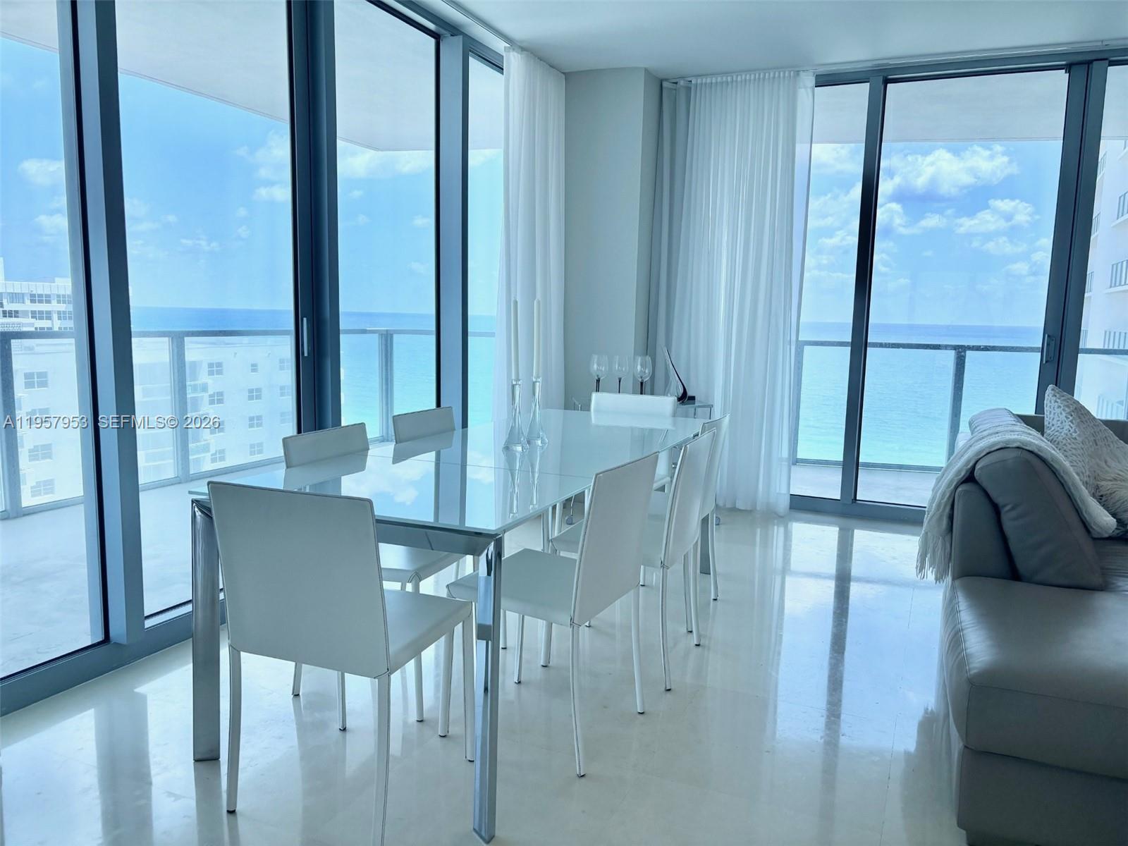 A modern dining area features a glass table, white chairs, and floor-to-ceiling ocean views — 3101 S Ocean Dr # 1701, Hollywood FL 33019, HOLLYWOOD, FL