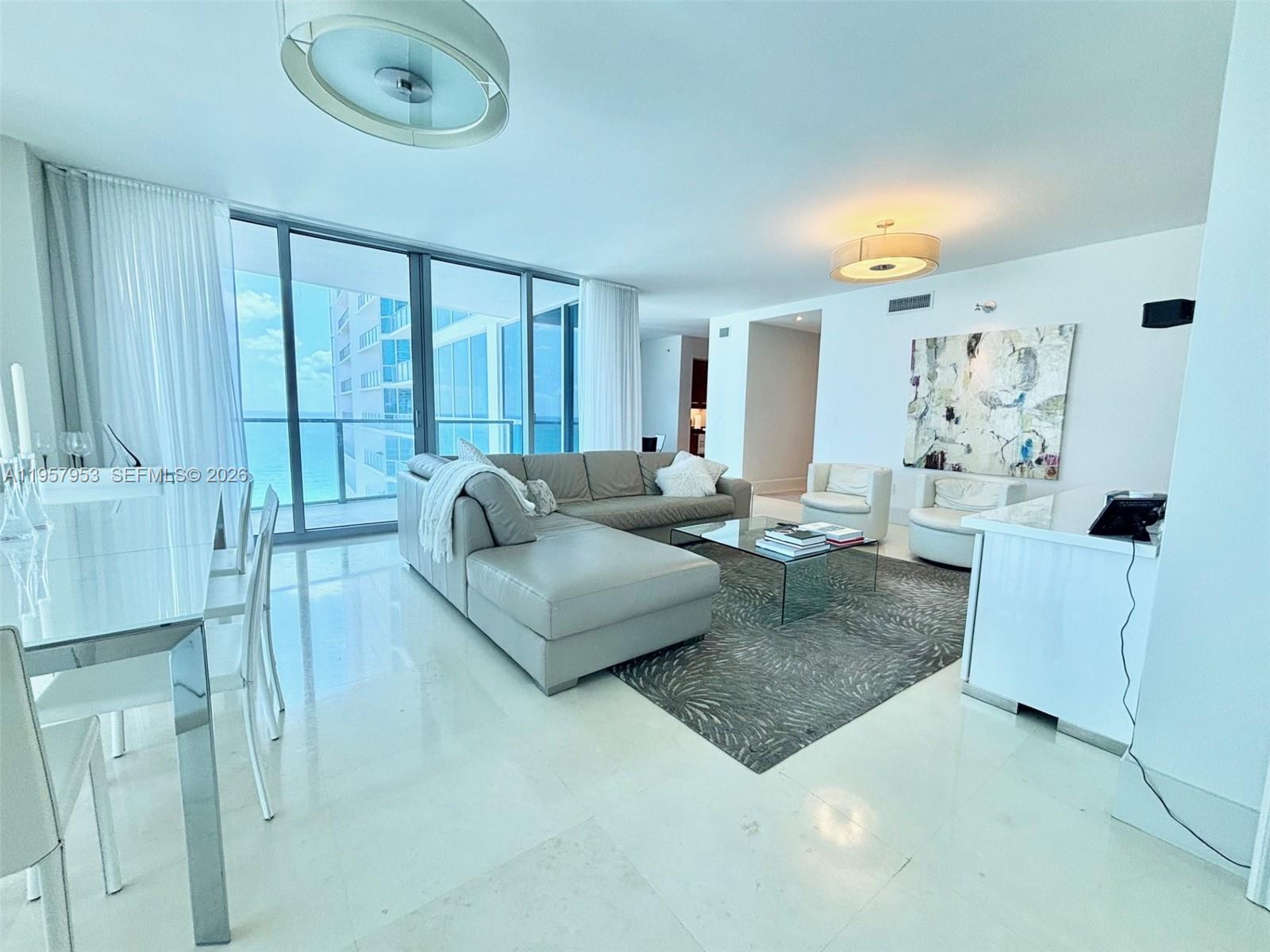 A modern living room features a gray sectional sofa, glass coffee table, and ocean views — 3101 S Ocean Dr # 1701, Hollywood FL 33019, HOLLYWOOD, FL