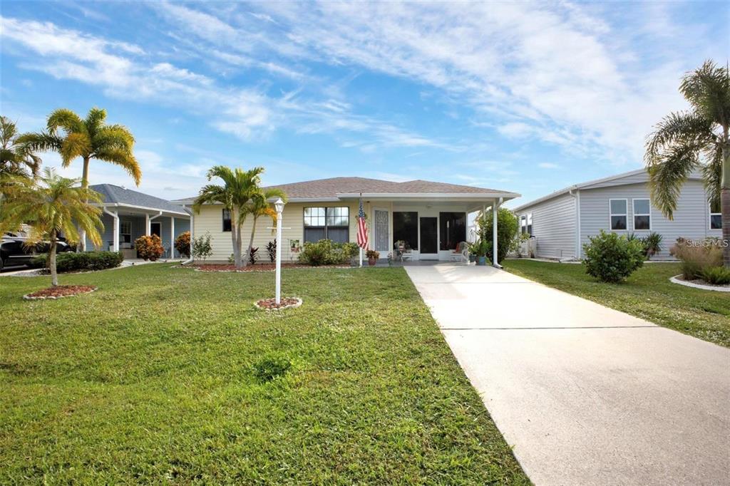 A single-story house with a light yellow exterior, a concrete driveway, and several palm trees — 3520 KENNETH ROAD, PORT CHARLOTTE, FL