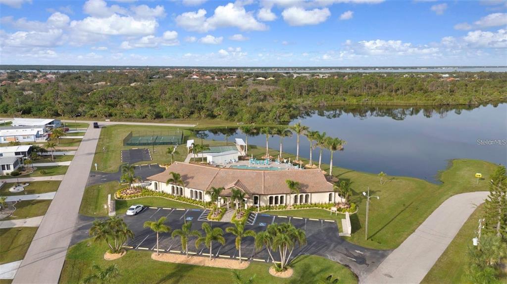 An aerial view shows a community clubhouse with a pool, tennis courts, and a lake — 3520 KENNETH ROAD, PORT CHARLOTTE, FL