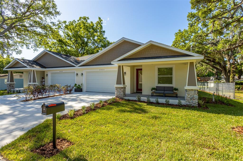 A single-story duplex with a concrete driveway, two garages, and a front porch with stone pillars — 11421 & 11423 WELDON STREET, SEFFNER, FL