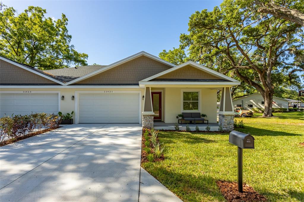 A single-story duplex with a concrete driveway, two garage doors, and a covered front porch — 11421 & 11423 WELDON STREET, SEFFNER, FL