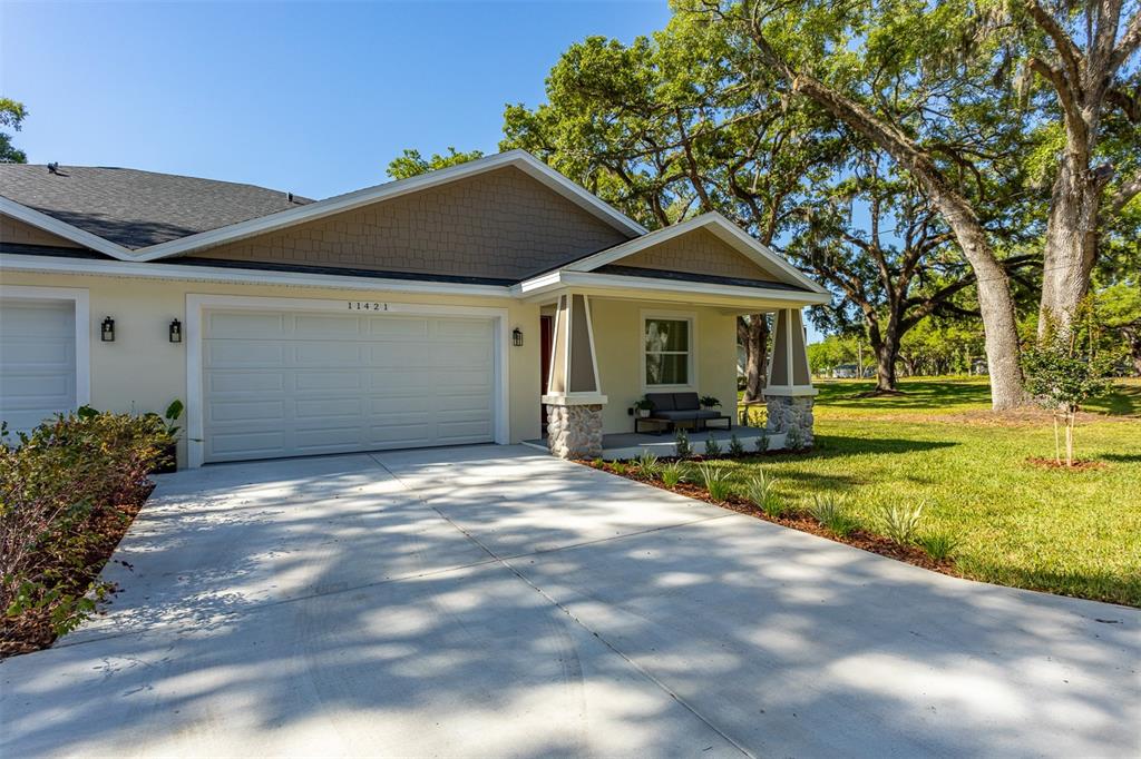 A single-story house exterior features a two-car garage, a covered front porch, and stone accents — 11421 & 11423 WELDON STREET, SEFFNER, FL
