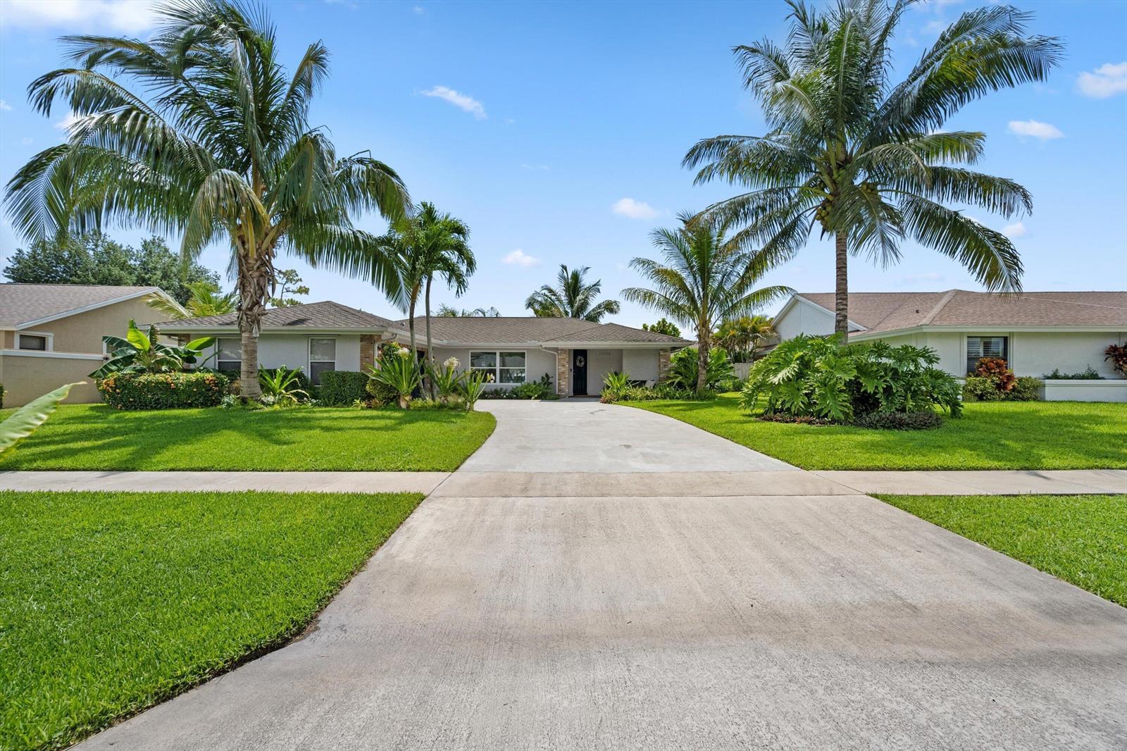 A single-story house with a concrete driveway, palm trees, and a green lawn — 14244 Horseshoe Trace, Wellington FL 33414, WELLINGTON, FL