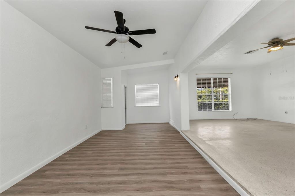 A living area with wood-look flooring and a sunken carpeted room beyond a partition wall — 21533 MIDWAY BOULEVARD, PORT CHARLOTTE, FL