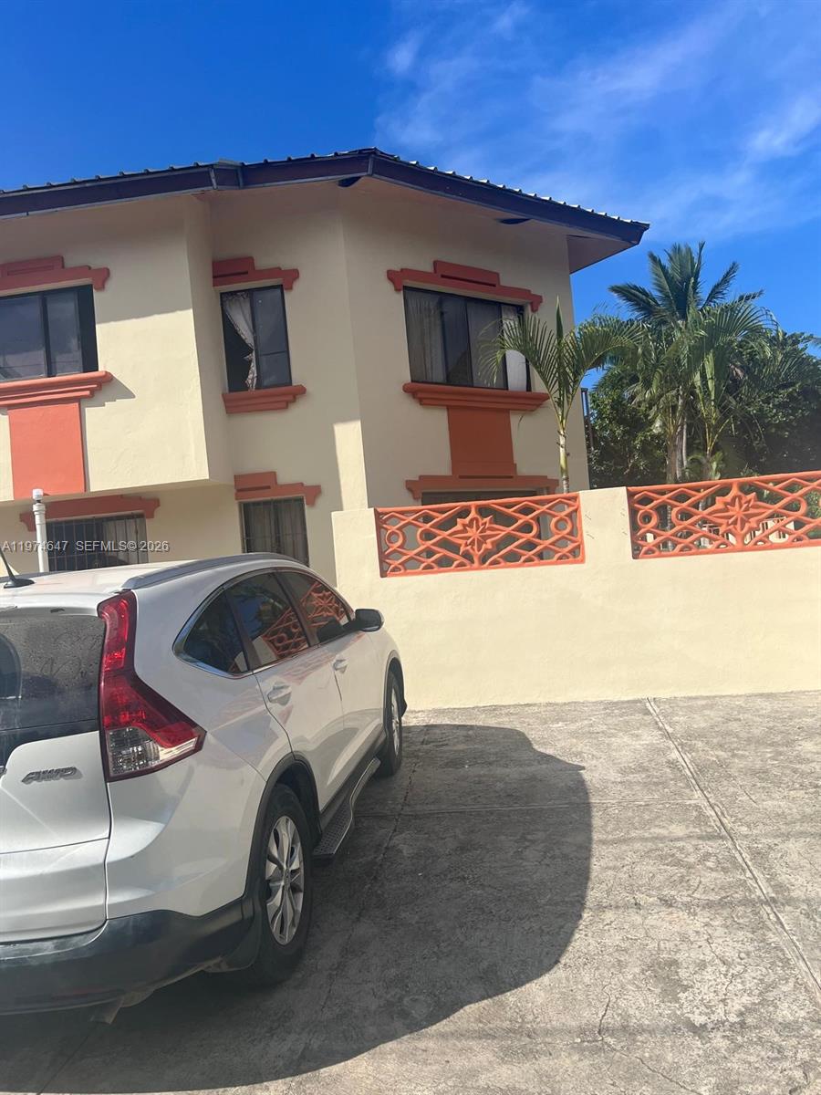 A white SUV is parked in front of a two-story house with orange trim — No.10 Calle Bohechio, DR foreign, DR
