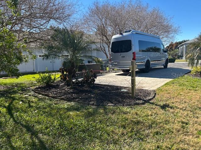 A silver van is parked on a paved driveway next to a landscaped garden bed — 427 TRAVELERS DRIVE, POLK CITY, FL