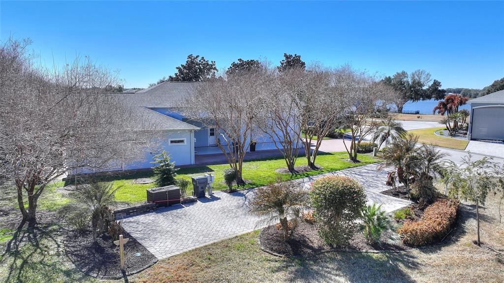 An exterior view shows a house with a paved driveway, landscaping, and a nearby lake — 427 TRAVELERS DRIVE, POLK CITY, FL