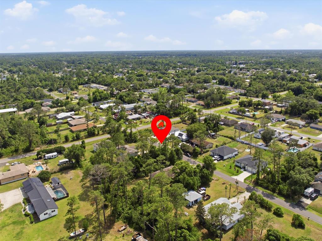 An aerial view shows a wooded residential lot marked by a red location pin — 1935 7TH AVENUE, DELAND, FL