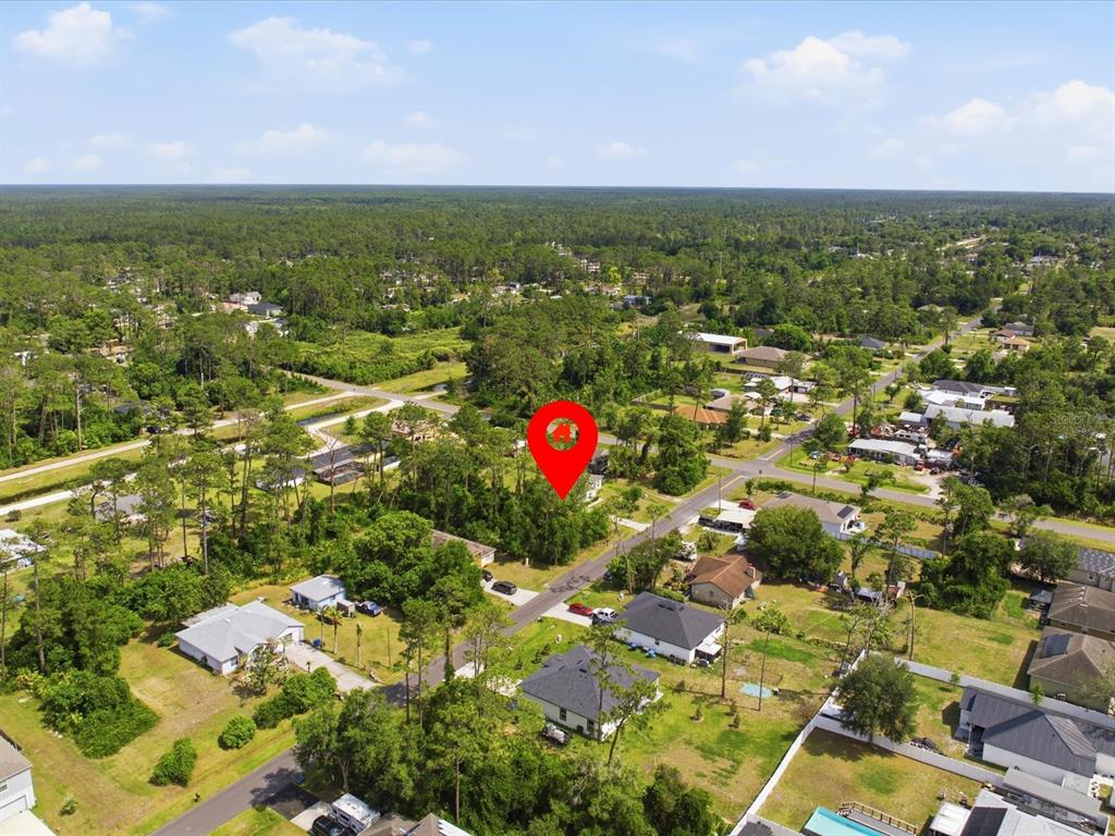 An aerial view shows a red location pin over a wooded lot in a neighborhood — 1935 7TH AVENUE, DELAND, FL