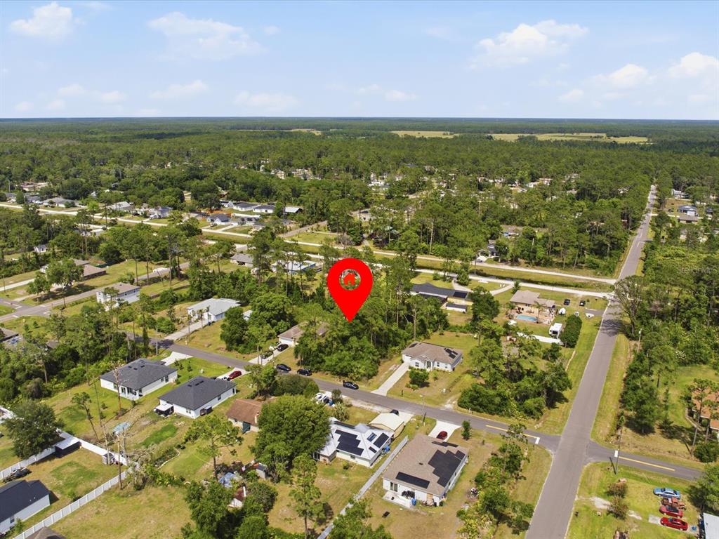 An aerial view shows a red location pin over a wooded residential lot — 1935 7TH AVENUE, DELAND, FL