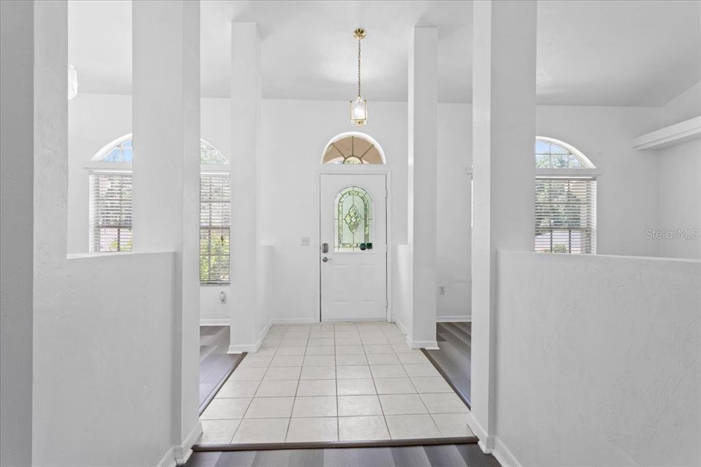 A bright entryway features white walls, tiled flooring, and a glass-paneled front door — 10336 NW 13TH AVENUE, GAINESVILLE, FL