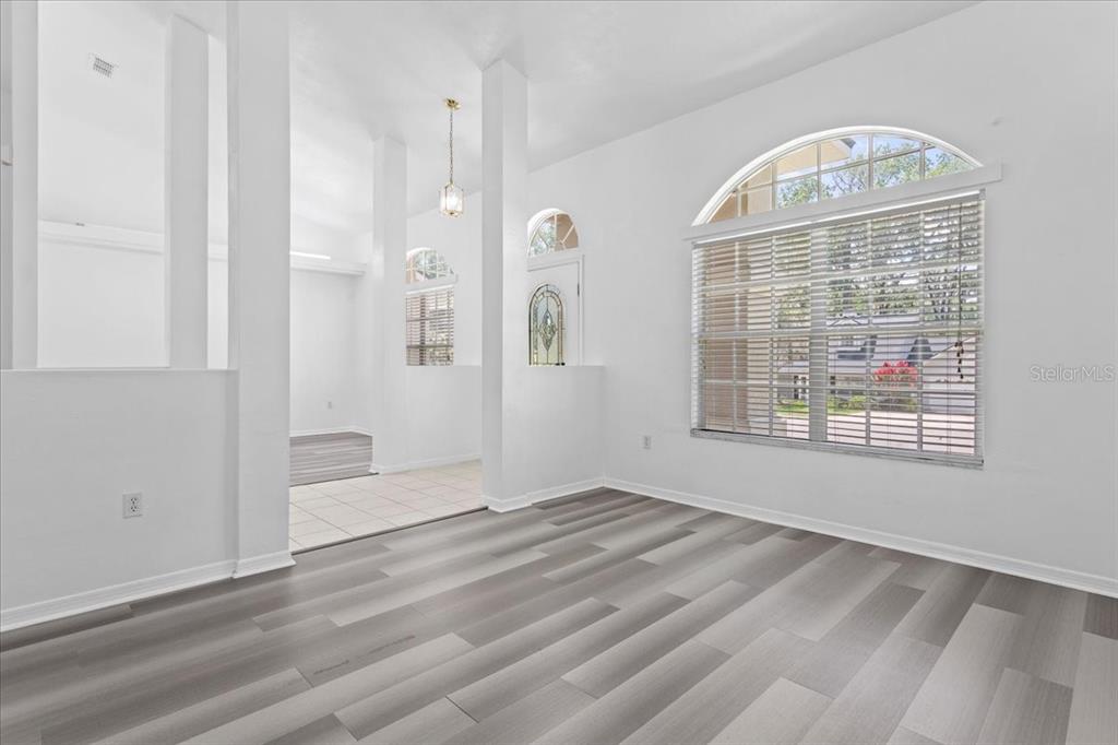 A bright room with gray wood-look flooring, white walls, and a large arched window — 10336 NW 13TH AVENUE, GAINESVILLE, FL