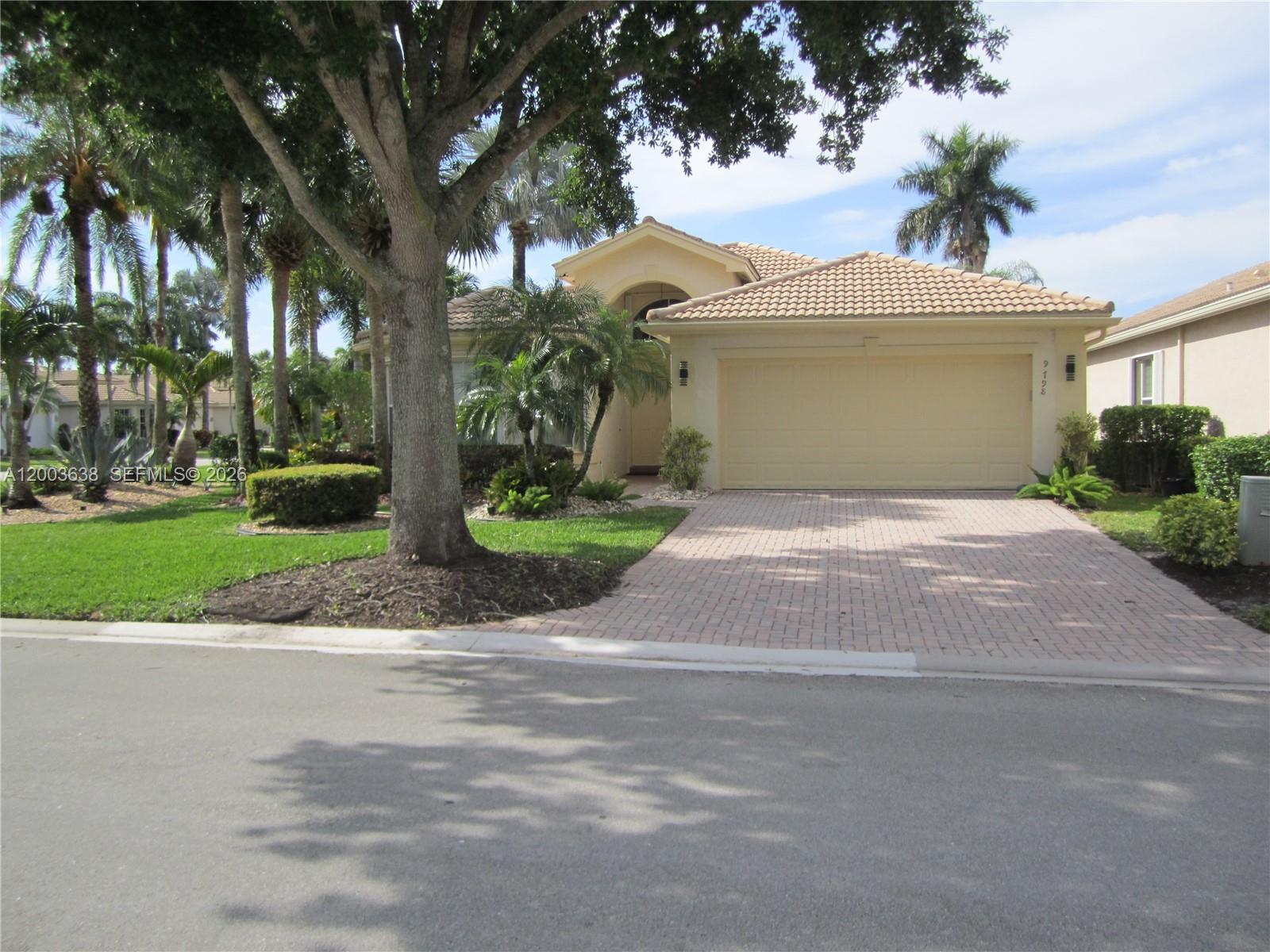 A single-story house with a beige stucco exterior, a tiled roof, and a paved driveway — 9798 Casa Mar Dr, Lake Worth FL 33467, LAKE WORTH, FL
