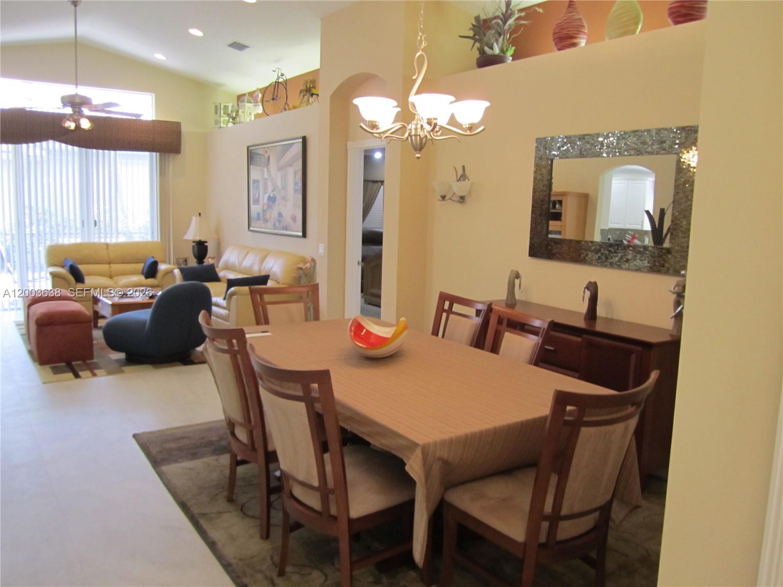 A dining area with a wooden table and chairs sits adjacent to a living room — 9798 Casa Mar Dr, Lake Worth FL 33467, LAKE WORTH, FL