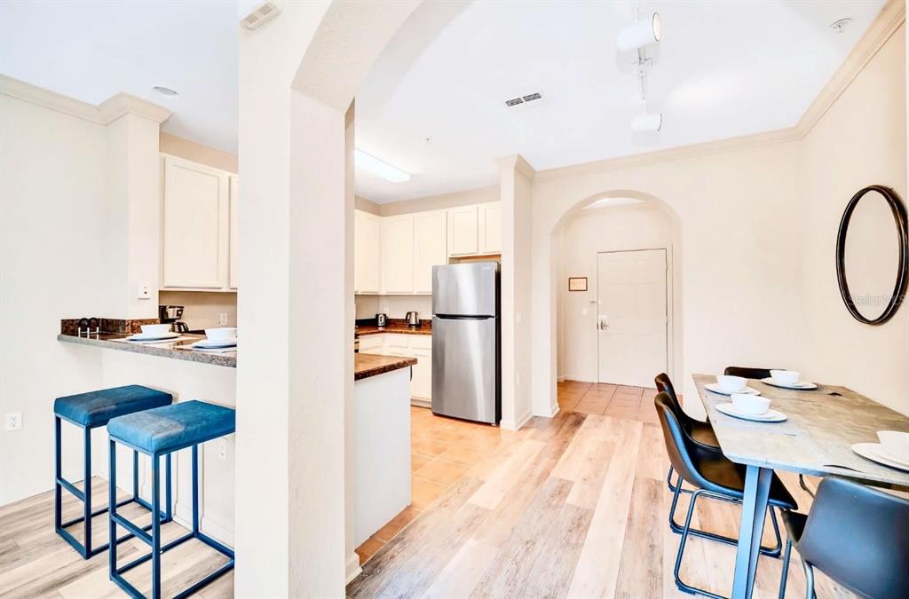 A kitchen with a breakfast bar and dining area featuring wood-look flooring and stainless appliances — 14200 AVALON ROAD UNIT 426, WINTER GARDEN, FL