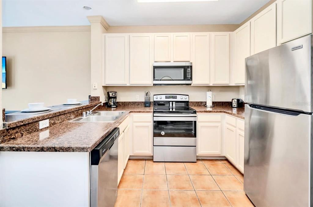 A kitchen with off-white cabinets, stainless steel appliances, and brown granite countertops — 14200 AVALON ROAD UNIT 426, WINTER GARDEN, FL