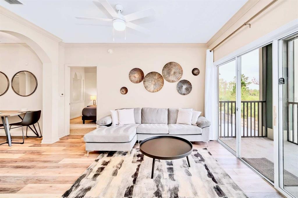 A living room features a gray sectional sofa, a round coffee table, and wall art — 14200 AVALON ROAD UNIT 426, WINTER GARDEN, FL