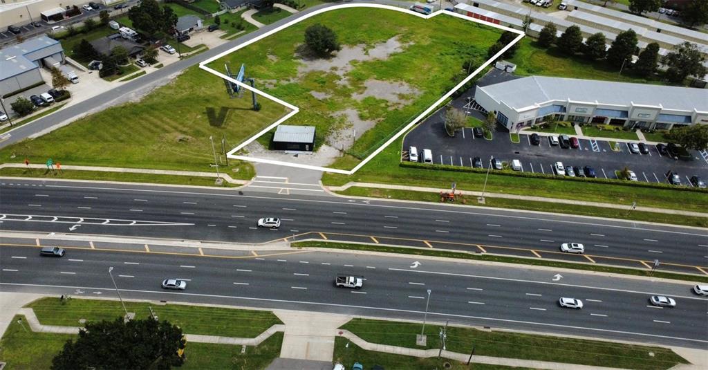 An aerial view shows a vacant, grass-covered lot outlined in white next to a commercial building — BROADVIEW DRIVE, KISSIMMEE, FL