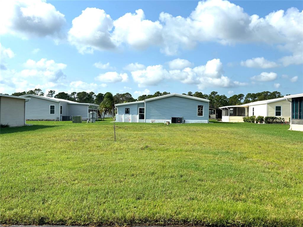 A grassy lot sits in front of several single-story manufactured homes under a blue sky — 705 DEL LUNA DRIVE, NORTH PORT, FL