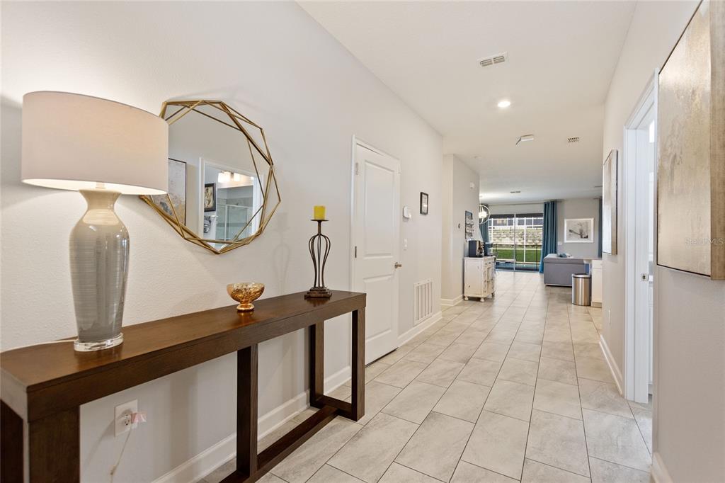 A tiled entryway features a wooden console table, a geometric mirror, and a lamp — 1594 SANDBAGGER DRIVE, DAVENPORT, FL