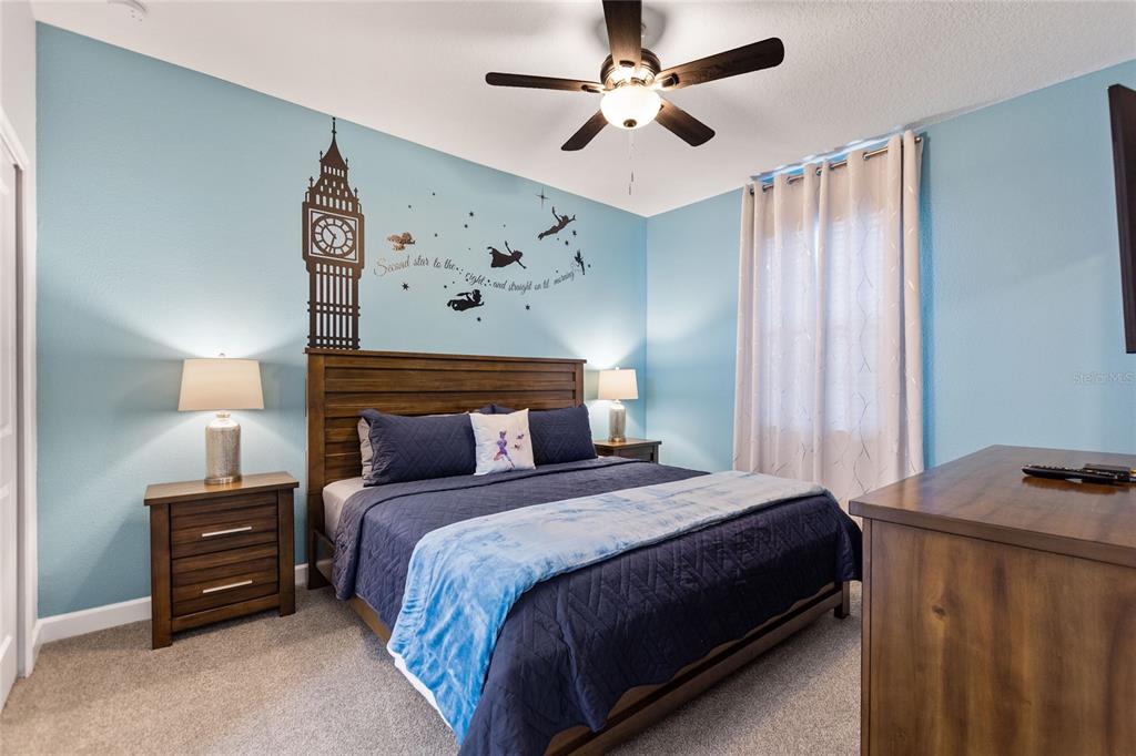 A bedroom features a Peter Pan wall decal, a wooden bed frame, and light blue walls — 1594 SANDBAGGER DRIVE, DAVENPORT, FL