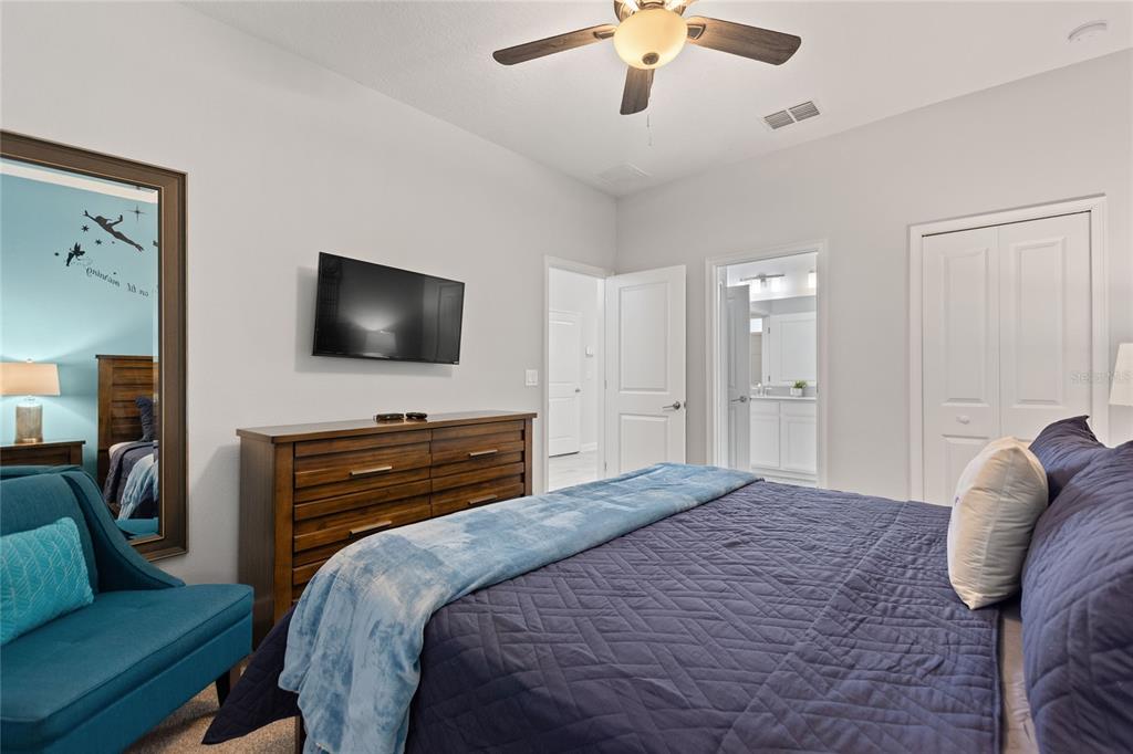 A bedroom features a bed with a blue quilt, a wooden dresser, and a television — 1594 SANDBAGGER DRIVE, DAVENPORT, FL