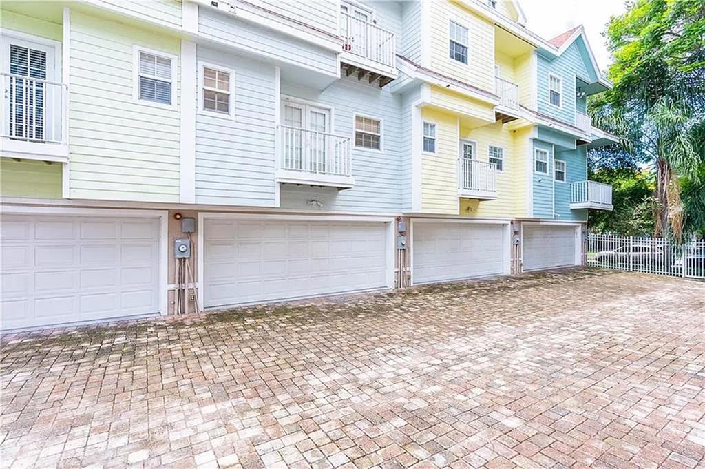 A multi-story building with pastel siding features several garage doors and balconies above a paved driveway — 827 GROVE STREET N, ST PETERSBURG, FL