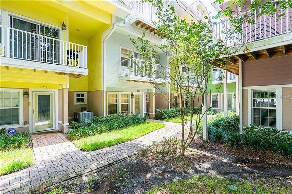 A view of the exterior of multi-story townhomes with balconies and a brick walkway — 827 GROVE STREET N, ST PETERSBURG, FL