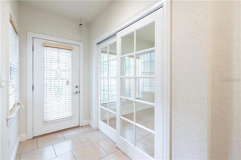 A tiled entryway features a white exterior door and a set of glass-paned sliding doors — 827 GROVE STREET N, ST PETERSBURG, FL