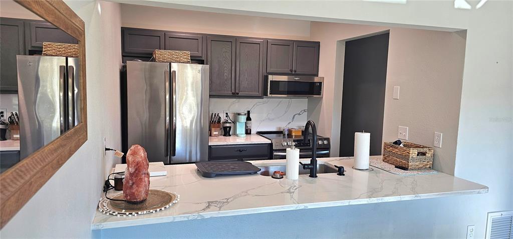 A kitchen features dark gray cabinets, stainless steel appliances, and a white marble-patterned countertop — 3775 59TH AVENUE W UNIT 3775, BRADENTON, FL