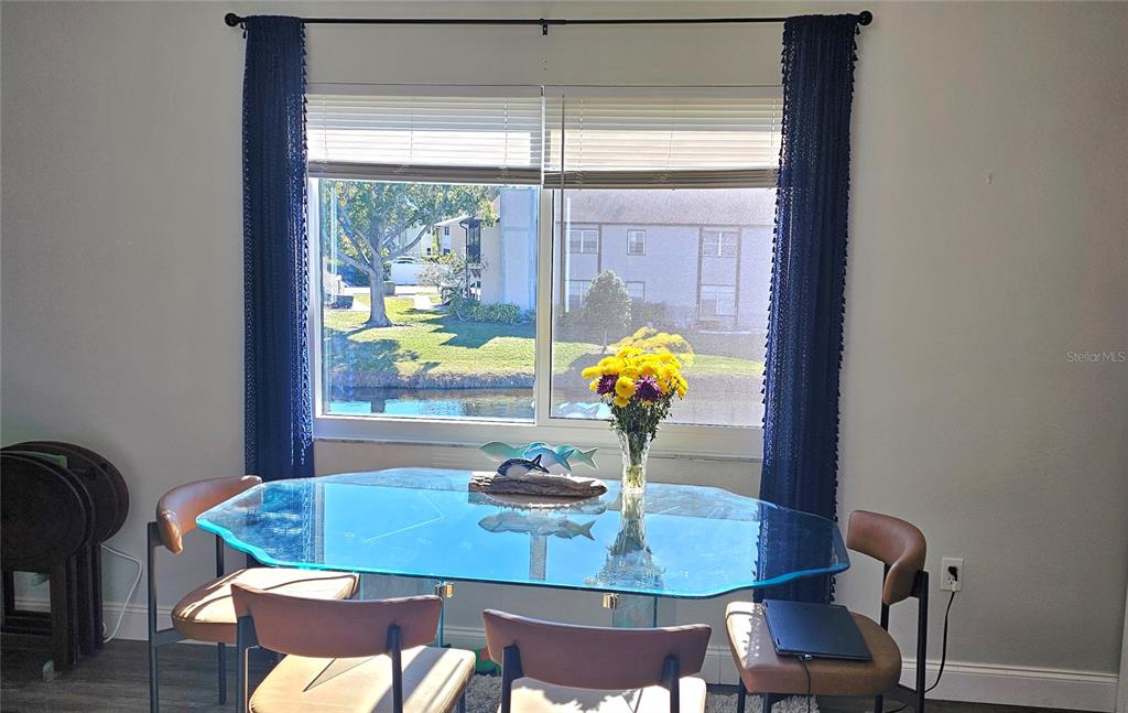 A dining area features a glass-topped table, tan chairs, and a window overlooking a canal — 3775 59TH AVENUE W UNIT 3775, BRADENTON, FL